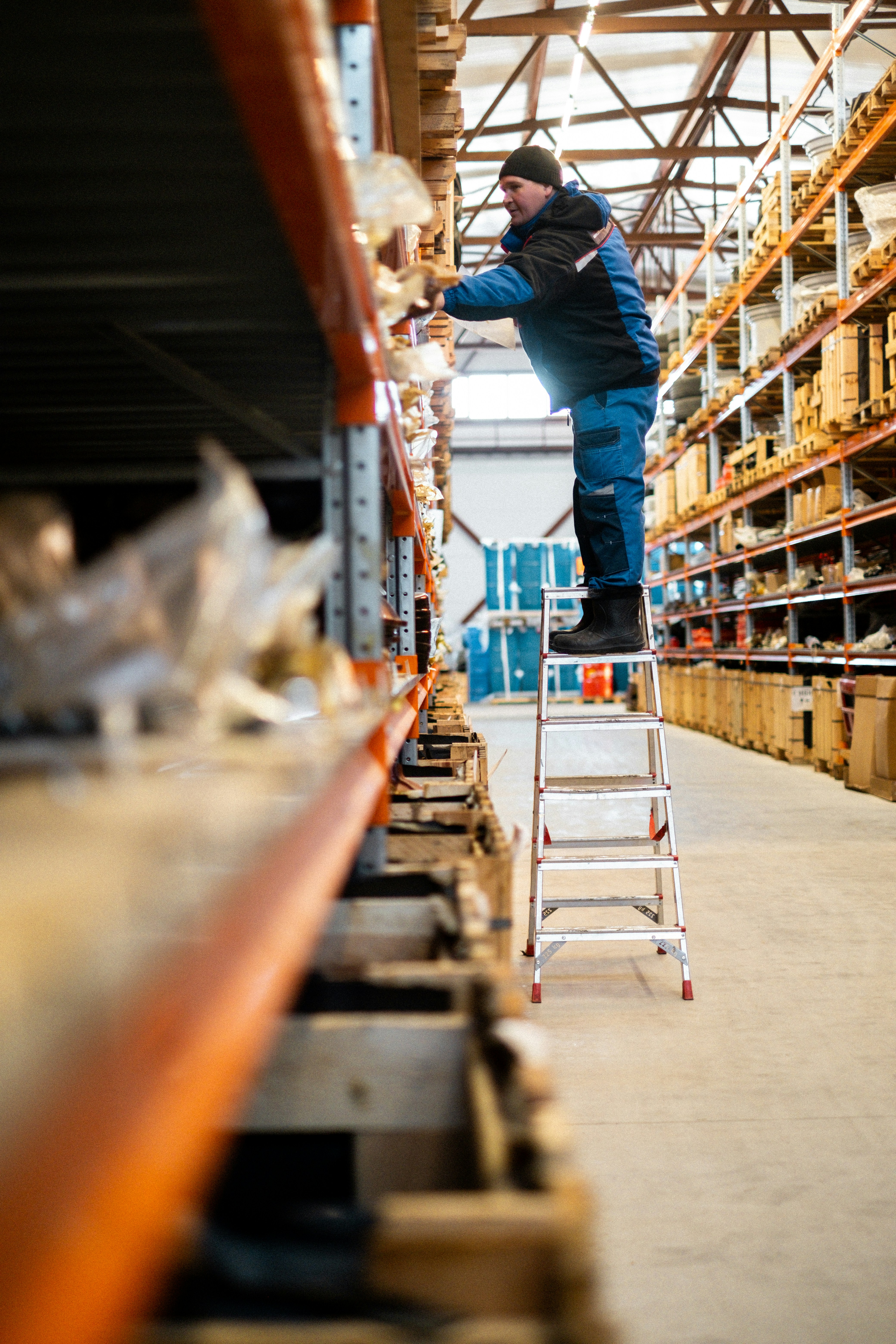 Warehouse Worker Organizing Inventory on a Ladder